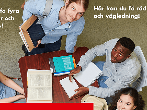 Bild tagen uppifrån. Tre personer sitter på varsin sida av ett bord med block och pennor på. En person står upp vid änden av bordet. Alla tittar uppåt mot kameran.