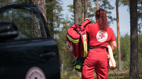 En kvinna stegar in i skogen med krisutrustning vid skogsbrand